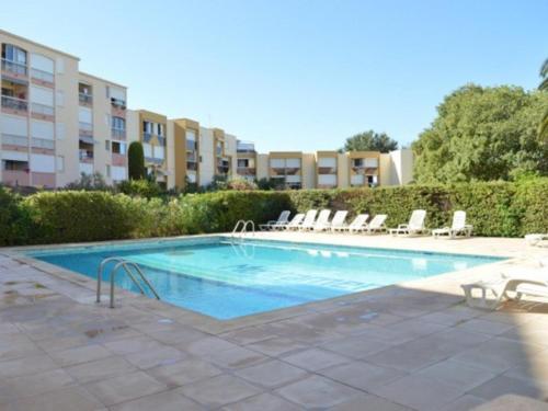 a swimming pool with lounge chairs and a building at Appartement Le Grau-du-Roi, 2 pièces, 4 personnes - FR-1-307-158 in Le Grau-du-Roi