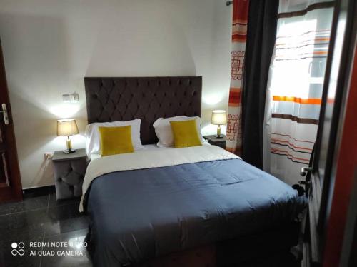 ein Schlafzimmer mit einem großen Bett mit zwei gelben Kissen in der Unterkunft FIRST RESIDENCE KRIBI in Kribi