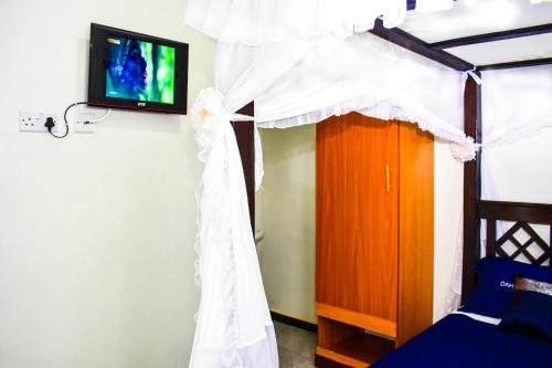 a bedroom with a bed with a canopy and a tv at Dahlia Hotel and Accommodation in Homa Bay