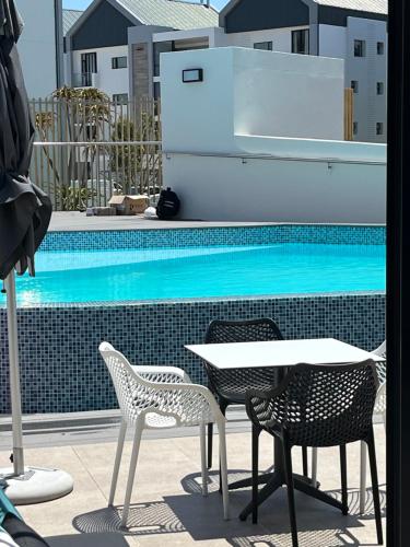 a table and chairs next to a swimming pool at Flat 14 Block 6 Bellamare in Port Elizabeth