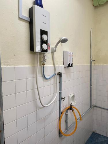a shower in a tiled bathroom with a hose at Pelangi Capsule Hostel in Johor Bahru
