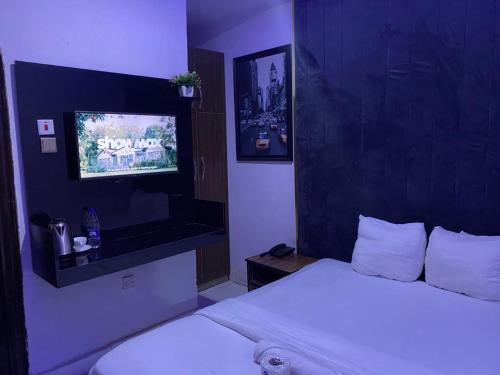 a bedroom with a white bed and a tv at Palazzo Apartments in Ikeja