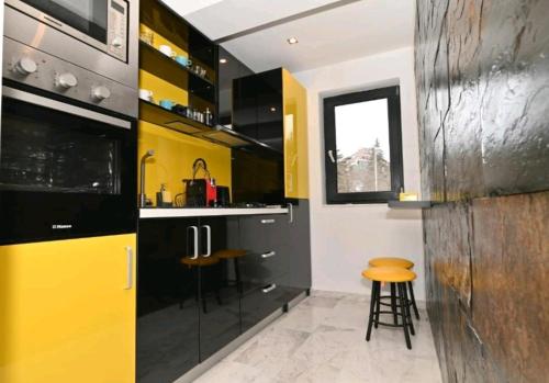 una cocina con armarios y taburetes amarillos y negros en R&B Studio, en Predeal
