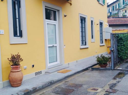 佛羅倫斯的住宿－Francarooms，黄色的建筑,有窗户,人行道上有一个花瓶