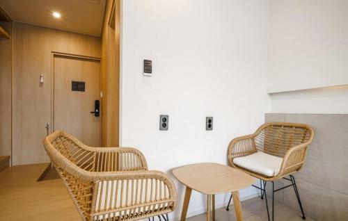 two wicker chairs and a table in a room at Geoje Mongdol Beach H Avenue Hotel in Geoje 