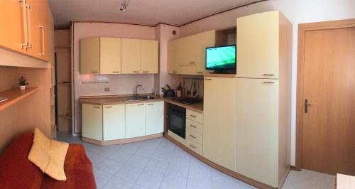 a kitchen with white cabinets and a flat screen tv at Ruscello apartment in Abetone