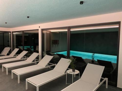 a room with white lounge chairs and a pool at Le Moulin de la Piérie in Neufchâteau