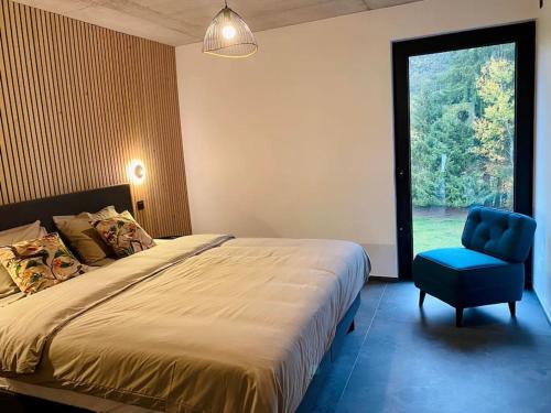een slaapkamer met een bed en een blauwe stoel en een raam bij Le Moulin de la Piérie in Neufchâteau