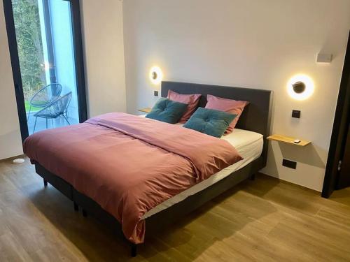 a bedroom with a large bed with pink and blue pillows at Le Moulin de la Piérie in Neufchâteau