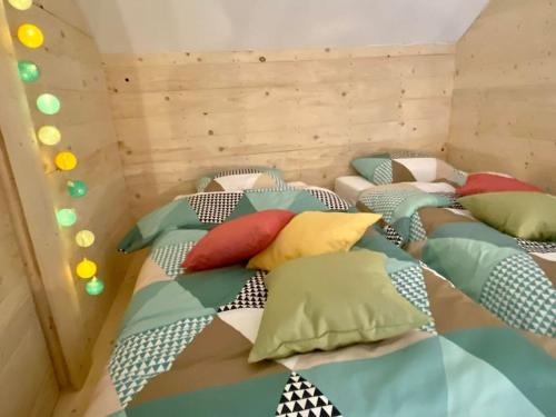 a room with four beds with colorful pillows on them at Le Moulin de la Piérie in Neufchâteau