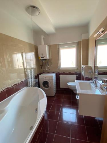 La salle de bains est pourvue de 2 lavabos, d'une baignoire et d'un lave-linge. dans l'établissement Bella Apartman, à Balatonfüred