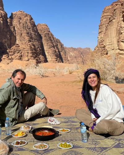 a man and woman sitting at a table with food at RUM STARDUST lUXURY CAMP in Wadi Rum