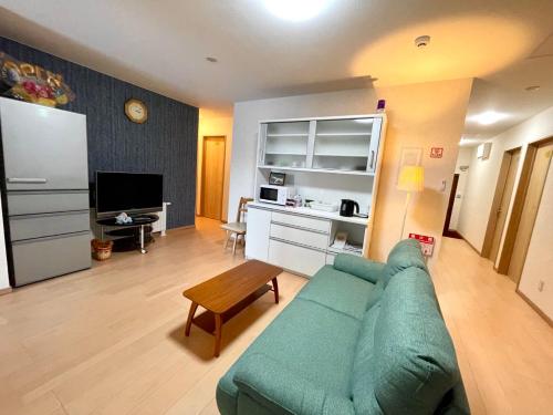 ein Wohnzimmer mit einem grünen Sofa und einem Tisch in der Unterkunft Otaru Garden Stay in Otaru