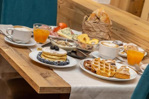 a table topped with plates of breakfast foods and cups of coffee at Hotel Pejo in Peio Fonti
