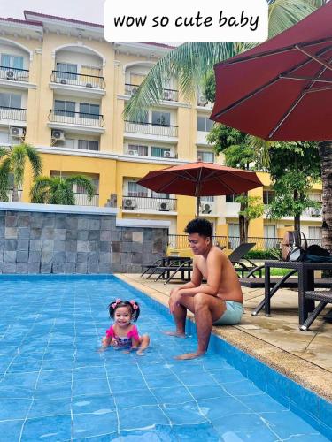 a man and a little girl in a swimming pool at Two-Bedroom at San Remo Oasis in Cebu City