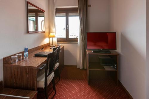 a room with a desk with a computer and a television at Hotel Lago Di Garda in Malcesine