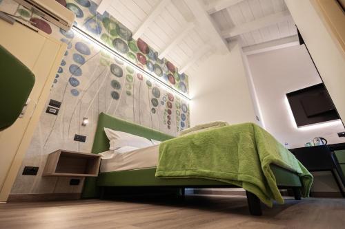 a bedroom with a green bed and a wall with plates at Hotel Lago Di Garda in Malcesine
