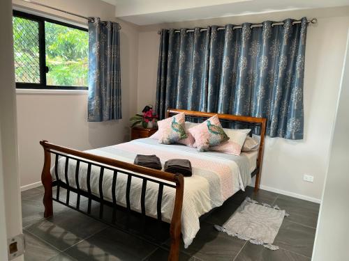 a bedroom with a bed with blue curtains and a window at The Frangipani Suite - One bedroom apartment in Cooktown in Cooktown
