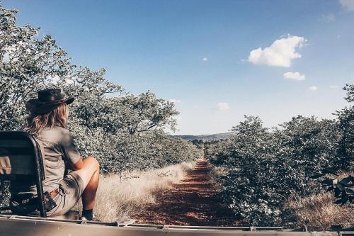 a woman sitting in the back of a truck on a dirt road at Baluleni Safari Lodge in Grietjie Nature Reserve