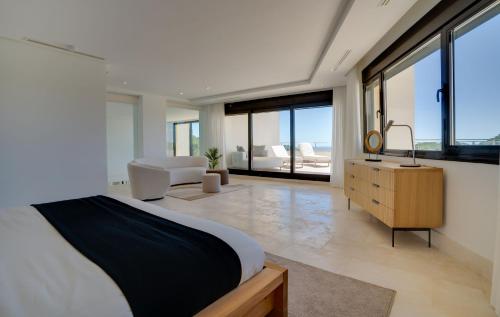Schlafzimmer mit einem Bett, einer Kommode und Fenstern in der Unterkunft Gravity- Luxurious paradise with sea view in San Roque