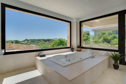 a large bathroom with a tub and large windows at Gravity- Luxurious paradise with sea view in San Roque