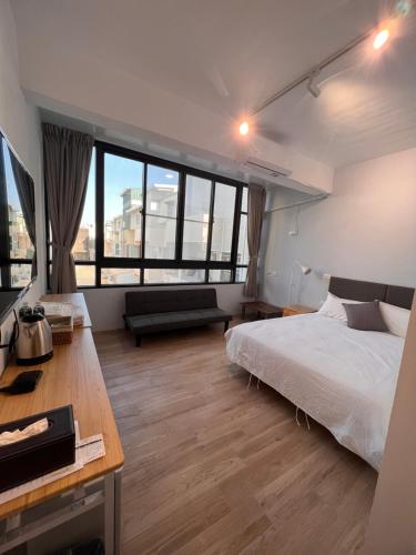 een slaapkamer met een bed, een bureau en ramen bij 茄萣路科民宿 