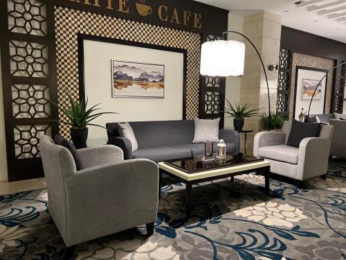 a lobby with couches and chairs and a coffee table at The Proud Hotel Al Khobar in Al Khobar