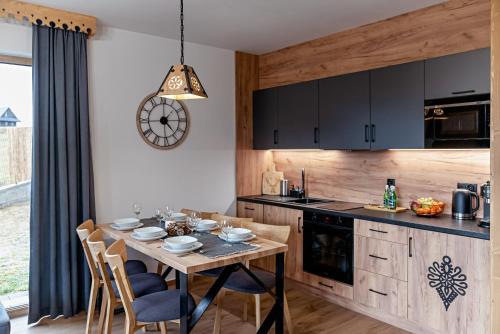 a kitchen with a table with chairs and a clock on the wall at Osada Wichrówka in Dursztyn