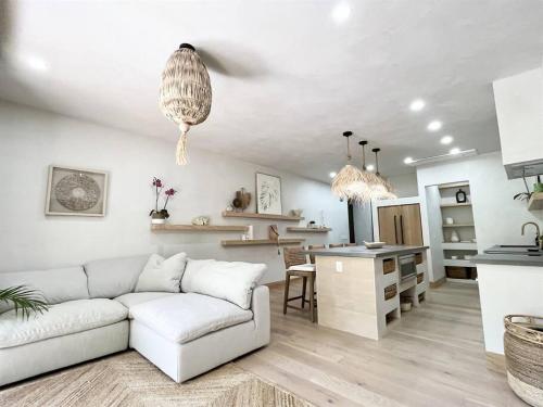 a living room with a white couch and a kitchen at Aloha Moon - A Chic and Dreamy Modern Tropical Hideaway! in Wailea