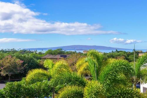 a view of the ocean from a resort with palm trees at Aloha Moon - A Chic and Dreamy Modern Tropical Hideaway! in Wailea