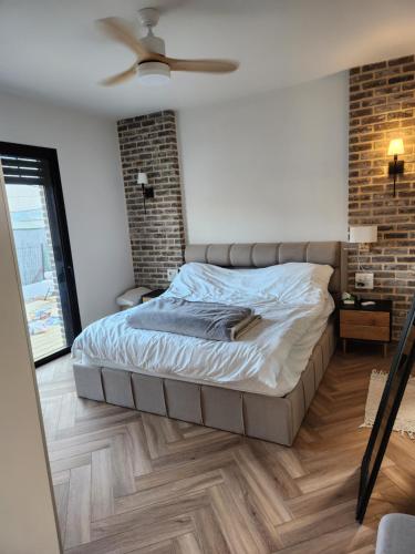 um quarto com uma cama e uma parede de tijolos em הפנינה האנגלית em Ramla