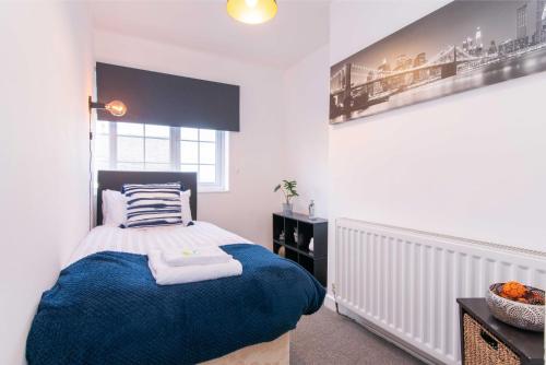 een slaapkamer met een bed met een blauwe deken bij Stylish & Central 2 bedroom apartment - Fast WiFi in Castle Donington