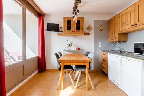 eine kleine Küche mit einem Holztisch und Stühlen in der Unterkunft Les gentianes 311 in Les Menuires