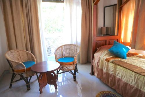 a bedroom with a bed and a table and chairs at Mango Tree House in Beruwala