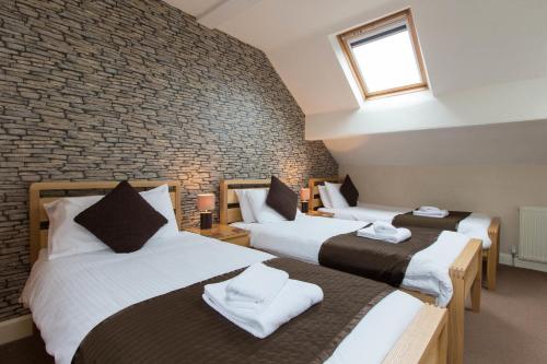 three beds in a room with a brick wall at Thornbank House Offering Breakfast and with the use of Free Local Health Club in Windermere