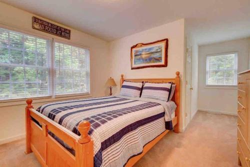 a bedroom with a wooden bed and two windows at Amazing Acorn in Diamond Point