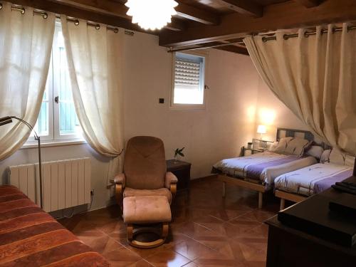 a bedroom with two beds and a chair and a window at Chambres à la Ferme de Pouzatel proche Bonaguil in Fumel