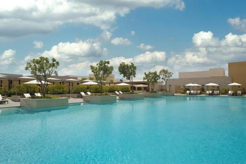 a large blue swimming pool with chairs and umbrellas at Fashion avenue - Formerly Address Dubai Mall Residence in Dubai