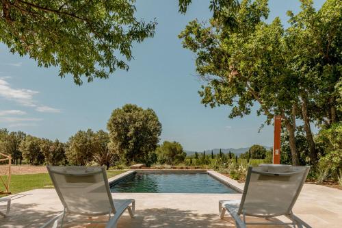 2 chaises assises en face d'une piscine dans l'établissement La Bastide Blanche au coeur des vignes Maison MIP, à Puyloubier