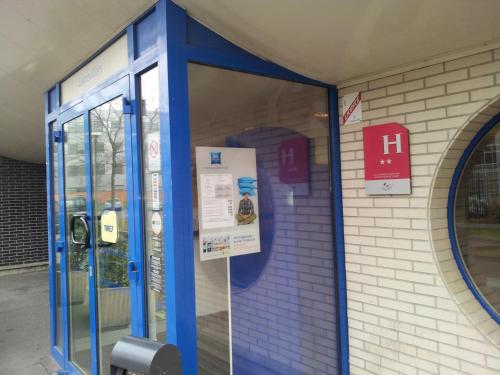 una entrada azul a un edificio con un teléfono de pago en ibis Budget Gennevilliers Asnieres, en Gennevilliers