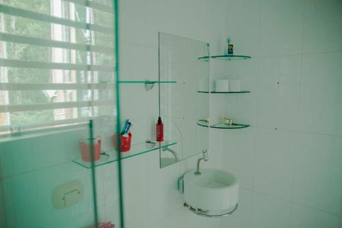 Baño blanco con lavabo y estanterías de cristal en Casa de Campo com Piscina e lazer em Cascavel PR, en Cascavel