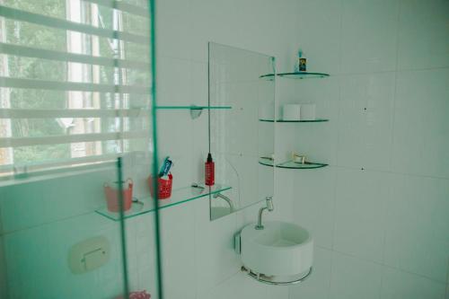a white bathroom with a sink and glass shelves at Casa de Campo com Piscina e lazer em Cascavel PR in Cascavel