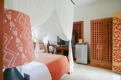 a bedroom with a bed with white curtains and a desk at Gayatri in Ubud