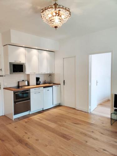 une cuisine avec des armoires blanches et un lustre dans l'établissement Top floor nest, balcony close to sea and old-town, à Nice