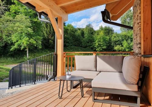 a wooden deck with a couch and a table at Nest Lodge in Weissbriach