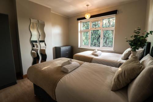 - une chambre avec 2 lits et une fenêtre dans l'établissement Cosy contractor house with FREE parking!, à Luton