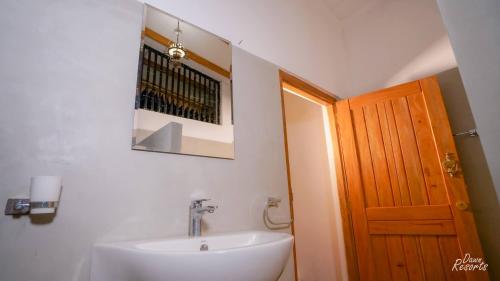 een badkamer met een wastafel, een spiegel en een deur bij Dawn Resorts in Elkaduwa