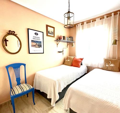 a bedroom with two beds and a blue chair at Casa Nuez Moscada in Villamartin