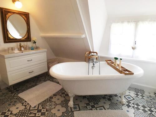 a bathroom with a tub and a sink and a mirror at La Romance et la Romanesque in Berville-sur-Mer