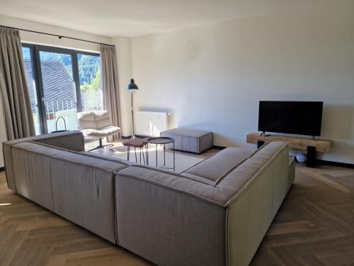 ein Wohnzimmer mit einem großen Sofa und einem TV in der Unterkunft Weißbriach Lodge in Weissbriach